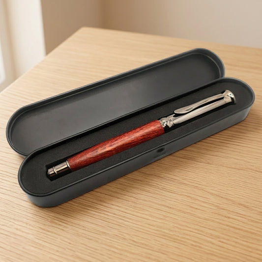 Stylo en bois à finitions métal gun dans son écrin en métal noir ouvert, intérieur en mousse noire, sur une table en bois – Weastyle Gravure