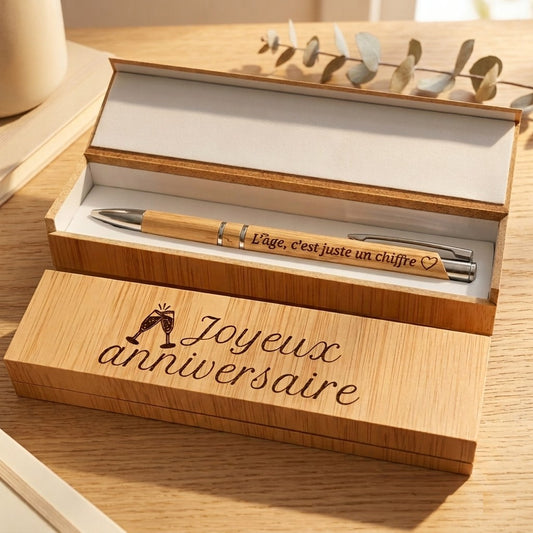 Coffret stylo bambou ouvert, couvercle gravé « Joyeux anniversaire » avec deux coupes de champagne, et stylo en bambou gravé « L'âge, c'est juste un chiffre » – Weastyle Gravure