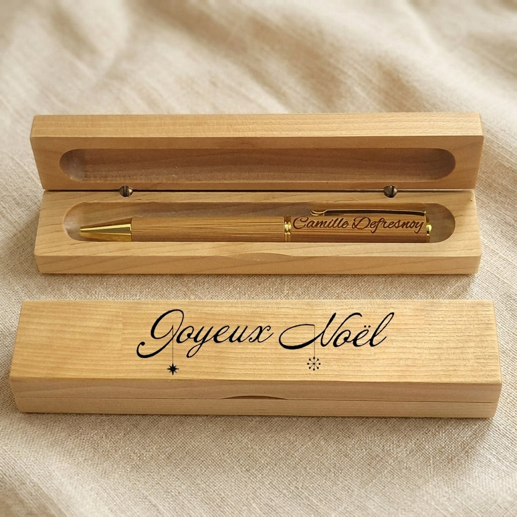 Coffret en bois ouvert avec un stylo à clip doré gravé « Camille Defresnoy », couvercle gravé « Joyeux Noël » – Weastyle Gravure