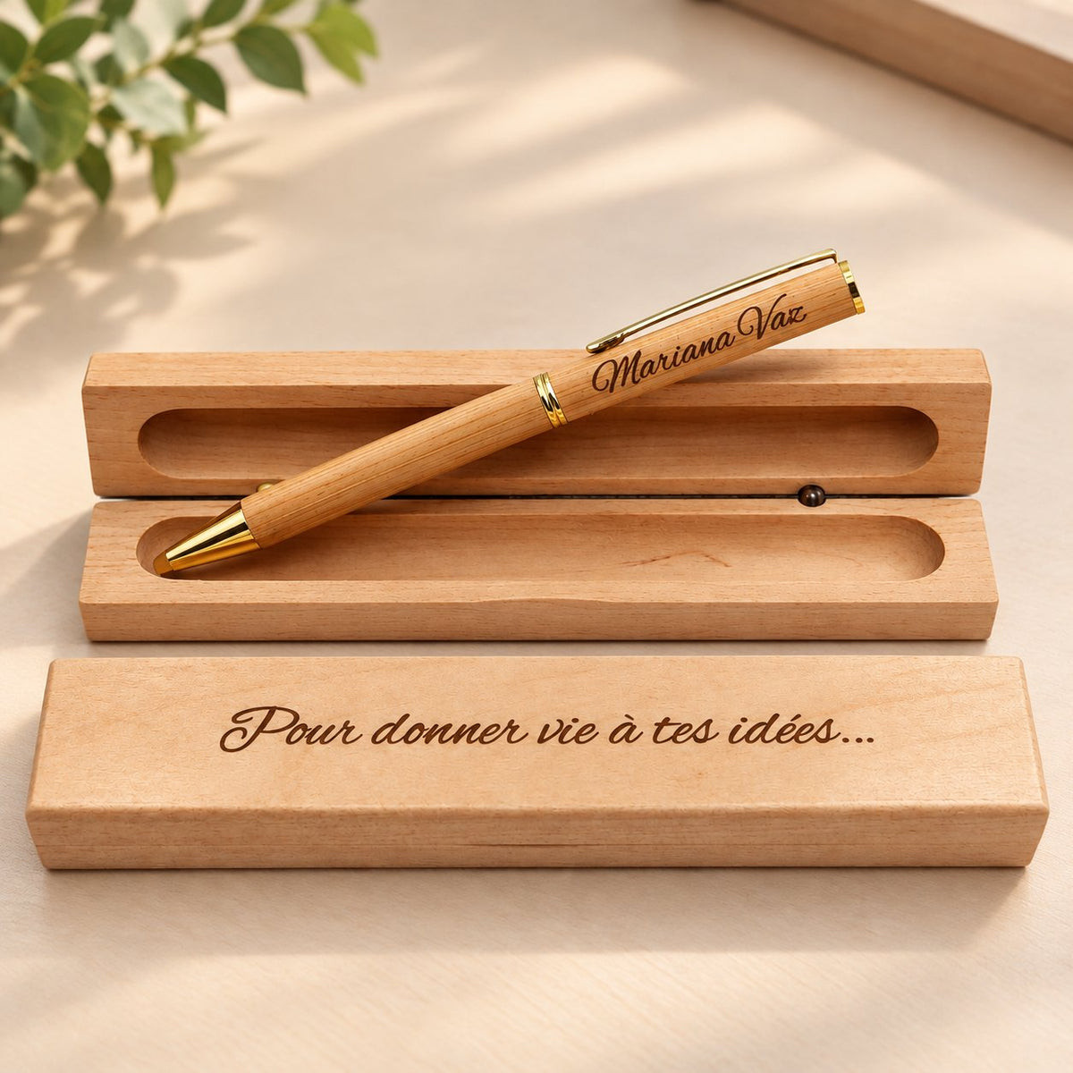 Stylo en bois à clip doré gravé « Mariana Vaz » posé sur son coffret en bois ouvert, couvercle gravé « Pour donner vie à tes idées… » – Weastyle Gravure