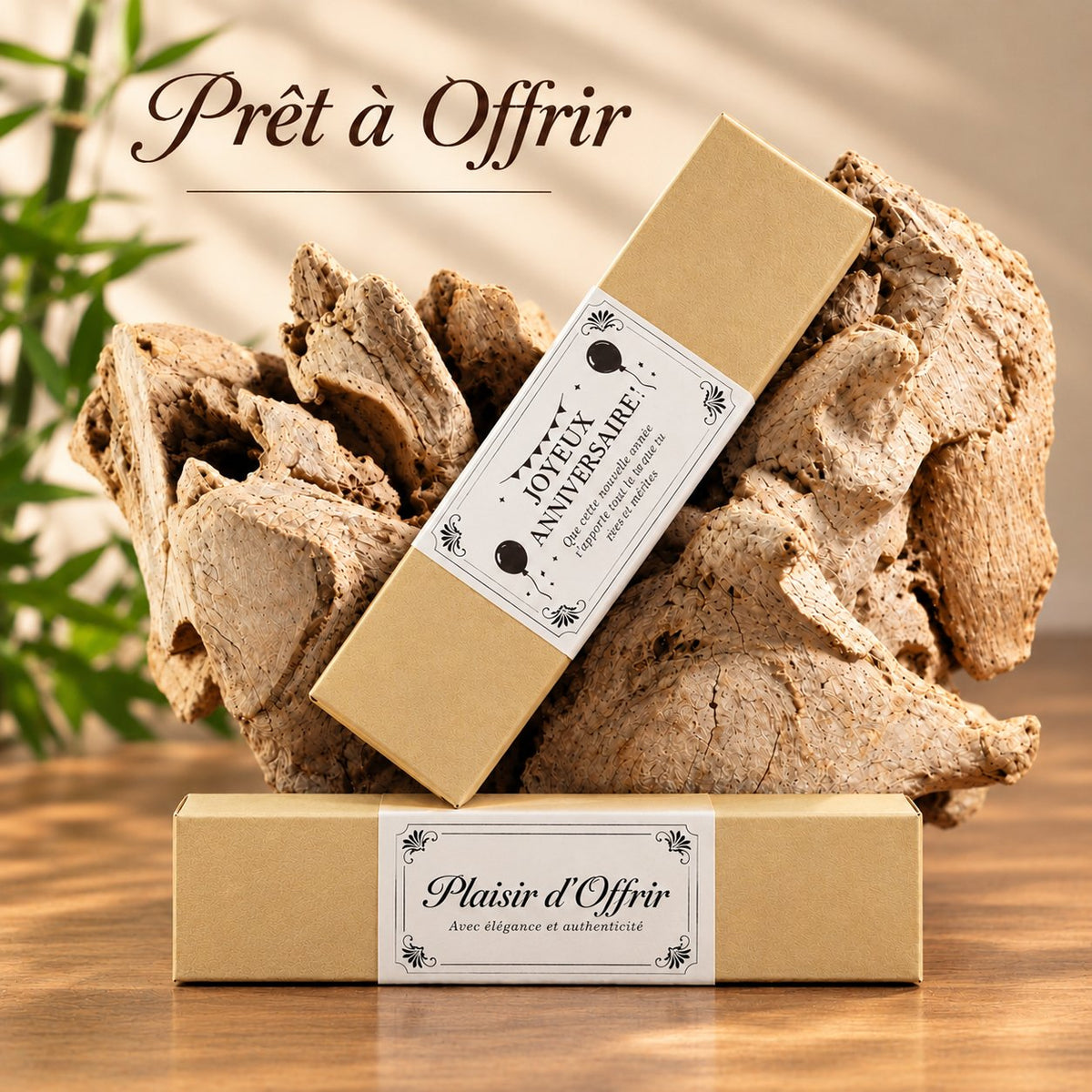 Deux coffrets cadeaux emballés dans un papier ocre clair, avec les étiquettes « Joyeux anniversaire » et « Plaisir d'Offrir », posés sur du bois flotté – Weastyle Gravure
