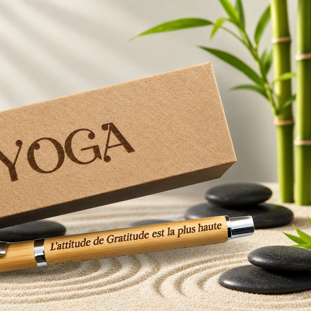 Stylo en bambou gravé d'une citation sur la gratitude, posé sur du sable zen devant un coffret kraft « Yoga » – Weastyle Gravure