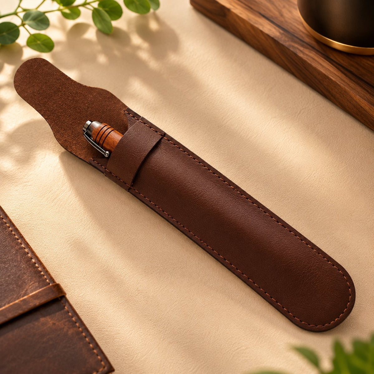 Étui marron à rabat et coutures apparentes avec un stylo en bois rotatif glissé à l'intérieur, sur un fond beige – Weastyle Gravure