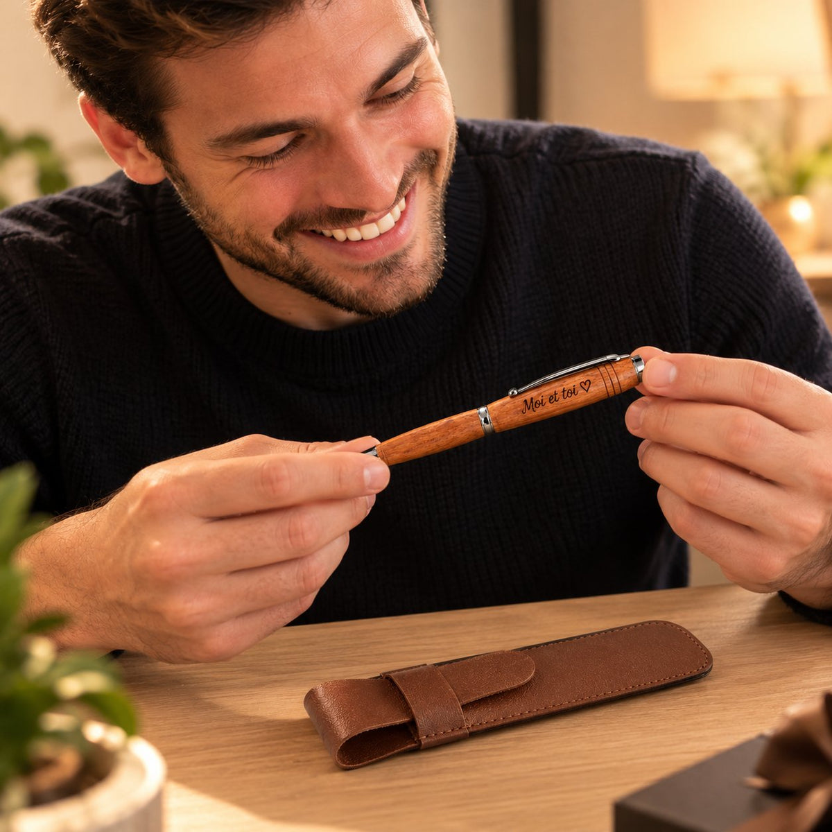 Homme souriant qui découvre un stylo en bois gravé « Moi et toi ♥ », avec son étui marron posé devant lui – Weastyle Gravure